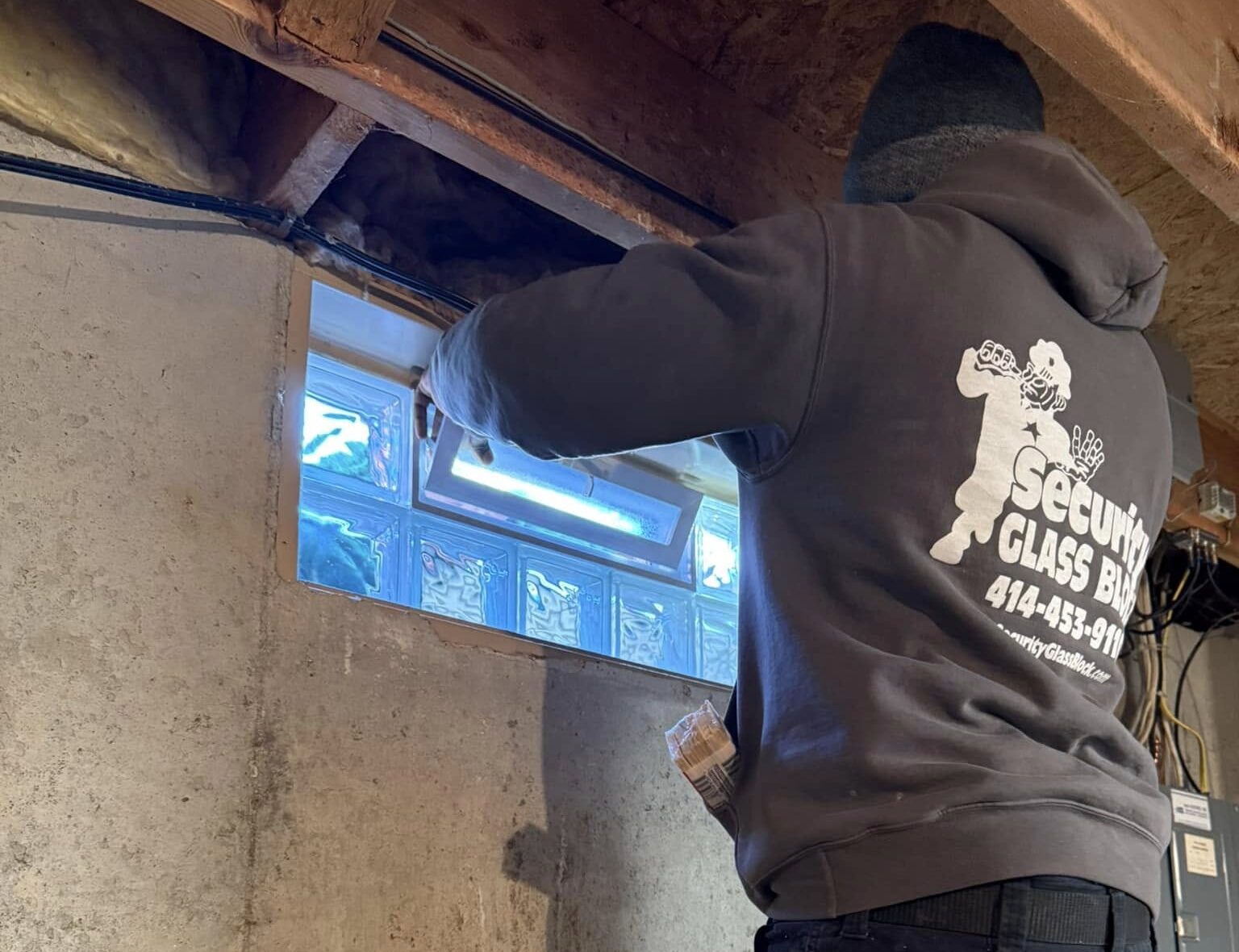 Man installing glass block window in a basement